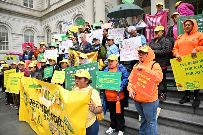 Street vendors gather at City Hall holding signs seeking street vending reform